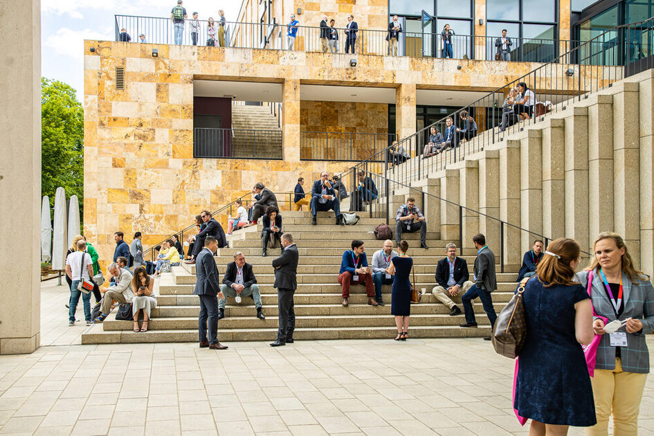 Kongressgäste verbringen ihre Pause an den Treppen vor dem RMCC
