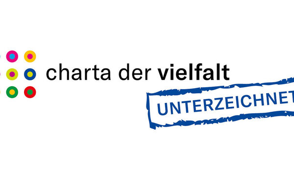 Charta der Vielfalt- Logo mit blauer/schwarzer Schrift, weißer Hintergrund und bunten Punkten.